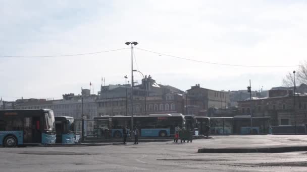 Eminonu, Istanbul, Turecko - 02.18.2021: velmi široký pohled na autobusové nádraží v Istanbulu a modré autobusy zaparkované pod modrým nebem a městský zaměstnanec řídí popelnici 4K s vysokým rozlišením — Stock video