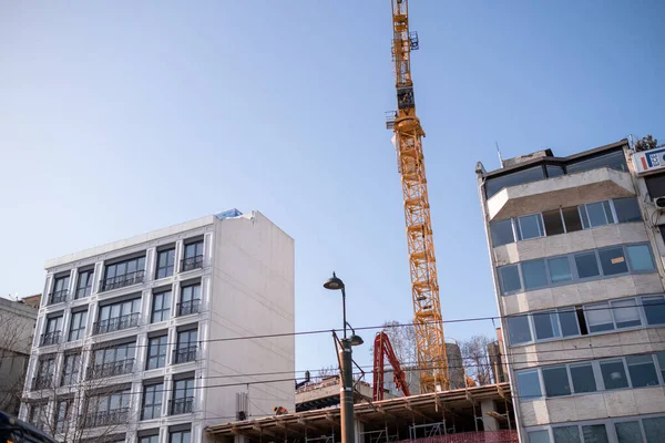 Kabatas, İstanbul, Türkiye - 02.26.2021: bulutsuz bir günde bazı binaların yakınında inşaat için sarı vinç alçak açısı