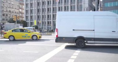 Beyoğlu, İstanbul, Türkiye - 03.17.2021: Bazı yayalar caddeyi ve belediye otobüsünü geçmek için trafik ışıklarını ve gün ışığında bir sürü arabanın geçmesini bekliyor