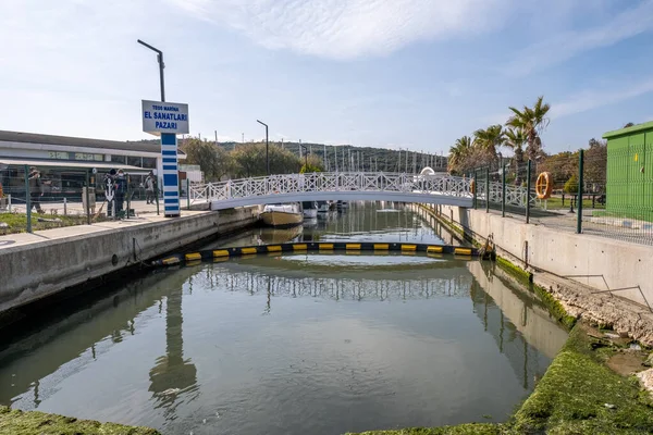 Seferihisar, İzmir, Türkiye - 03.08.2021: Bahar zamanı mavi gökyüzü altında parlak bir günde Teos Marina nehri. Tabeladaki çeviri: Teos El Sanatları Pazarı
