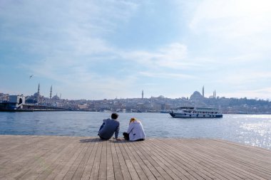 Eminonu, İstanbul, Türkiye - 04.13.2021: Marmara Denizi kıyısında oturan aşıklar ve baharda açık havada manzarayı izleyen çift