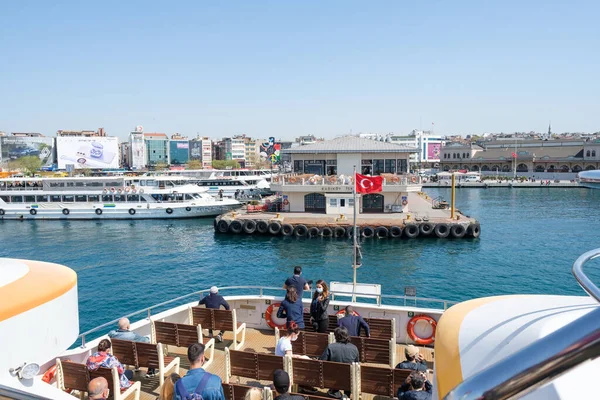 Kadıköy, İstanbul, Türkiye - 04.29.2021: Mavi deniz ve koruyucu maskeli yolcuların yüksek açılı feribot gemisi Kadıykoy limanına yanaşıyor.