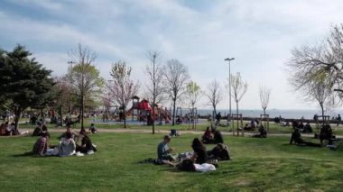 Kadıköy, İstanbul, Türkiye - 04.29.2021: Açık bir bahar günündeki karantina gününden önce Moda Halk Parkı 'nda çimlerin üzerinde oturup uzanan çok sayıda kişi