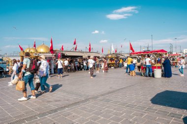 Eminonu, İstanbul, Türkiye - 07.05.2021: Eminonu Meydanı 'nda bir sürü Türk ve maskeli turist, yaz fotokopi alanında bayrakların altında balık kızartma satan tekne restoranlarıyla dolaşıyorlar