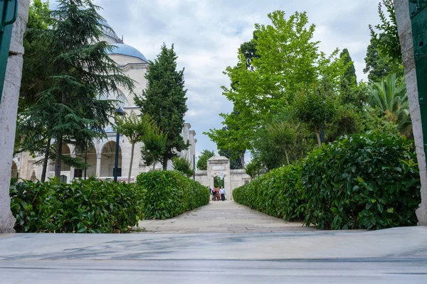 Fatih, İstanbul, Türkiye - 07.05.2021: Süleyman Camii 'nin kapısı ve bahçede bir sürü ağaç ve ziyaretçiler ve yaz günü elinde fotokopi aletiyle dolaşan farklı insanlar