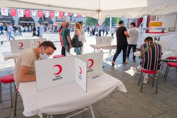 Eminonu, İstanbul, Türkiye - 07.05.2021: Türk Kızılayı (Türk Kizilay) logosu gönüllülerin kalabalık bir meydanda fotokopi alanı olan onay belgeleri imzaladığı beyaz masa üzerinde