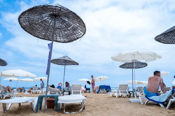 Sariyer, İstanbul, Türkiye - 07.17.2021: Kilyos plajı ve kıyı bölgesi, yaz tatilinde dinlenmek için güneşlenmek üzere birçok insanın saman şemsiyelerinin altına uzandığı kıyı bölgesi