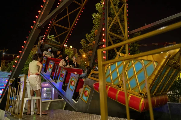 Maltepe, İstanbul, Türkiye - 07.22.2021: Çok sayıda Türk vatandaşı yaz günü eğlence amaçlı gece vakti sallanan bir korsan gemisi lunaparkında gezintiye çıktı