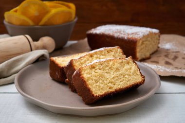 Tereyağı ve pudra şekerli turuncu kek. Kahvaltıdan sonra ya da tatlı olarak mükemmel bir seçim.