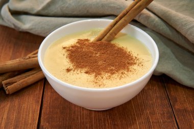 Tahta masanın üzerinde tarçınlı ev yapımı vanilyalı krema. Süt, yumurta, vanilya ve tarçınlı lezzetli bir tatlı. en üstteki görünüm