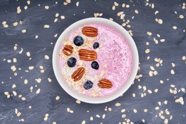 Yogurt bowl with oat, coconut, blueberries and nuts. a healthy breakfast over a grey background