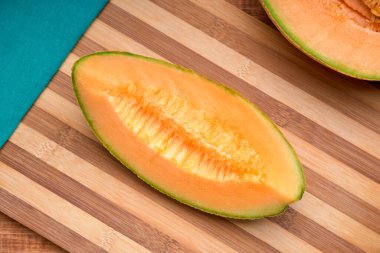 Kavun, bambu doğrama tahtasının üzerinde yeşil bez peçeteyle dilimlenmiş. en üstteki görünüm