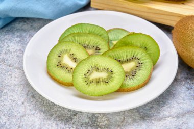 Beyaz bir tabakta dilimlenmiş kivi, mermer bir arka planda, yakın planda. Sağlıklı gıda konsepti. Diyet için ideal. egzotik meyve.