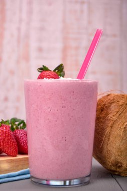 Çilekli ve hindistan cevizli smoothie, hindistan cevizli, çilekli ve pembe pipetli. Çilekli ve dipte bir hindistan cevizli. Reklam için kopyalama alanı ile.