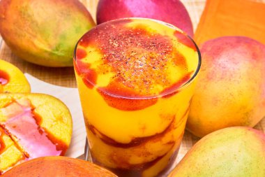 Chamoyada veya mango smoothie ve bambu pipetli, taze Meksika içeceği, ahşap bir masada tüm mangolarla servis edilir..