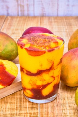 chamoyada or mango smoothie with chamoy, a mexican refreshing drink. served with mangoes with chamoy on a wooden table with a white wooden plank background. clipart