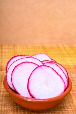 Ahşap bir yüzey ve ahşap bir zemin üzerinde toprak kapta turp dilimleri. Meksika yemeği konsepti. reklam için kopyalama alanı.