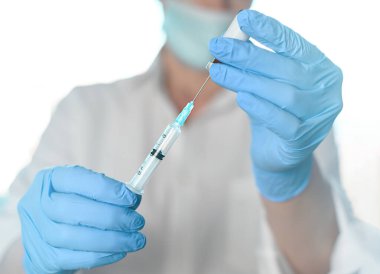 Kadın doktor ya da hemşire şırıngayı dolduruyor, aşıyı sıvı uyuşturucu ile tutuyor.