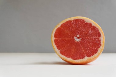 Gri arka planda taze organik pembe greyfurt dilimliyorum. Greyfurt yemek kandaki kolesterol seviyesini düşürür ve kilo kaybını arttırır. Beslenme düzeni. Minimalist kompozisyon.