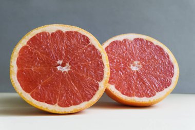 Parlak arkaplan minimalizmine karşı iki yarım pembe taze greyfurt.