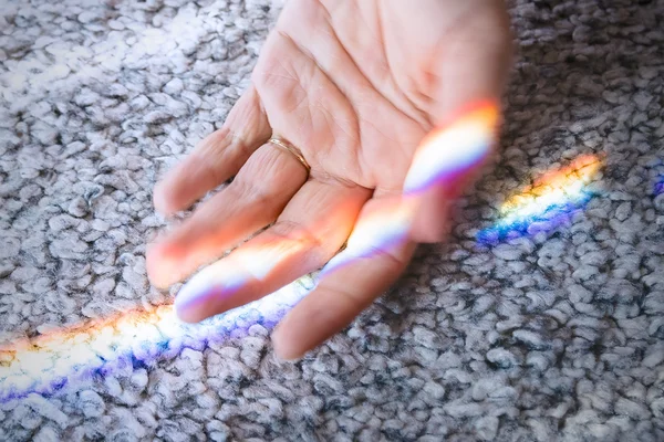 Mão feminina tocada pelo arco-íris — Fotografia de Stock