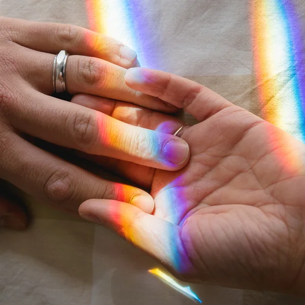 Mano nella mano con l'arcobaleno come legame Fotografia Stock