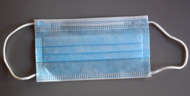 Gri arka planda mavi cerrahi maske.