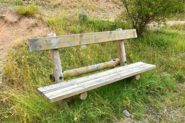 Dağın ortasında çimen olan ahşap bir bank..