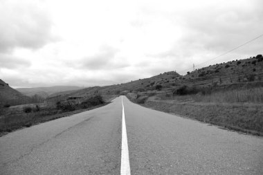 Asfalt yolu ve sürekli beyaz çizgi. Siyah beyaz fotoğraf.