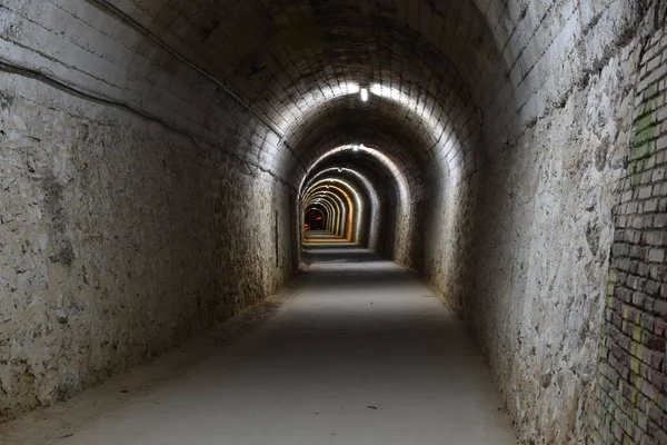 Section of the Arnedillo tunnel built in the rock, with brick and concrete. Lights of different colors and in the background the exit. Night photo.