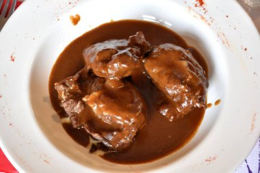 Kırmızı şarapta bir tabak domuz yanağı. Şarap sosu ve elma püresi..