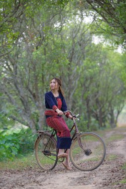 Eski bir bisikleti kabile içinde oturan genç Asyalı kadınlar pirinç elbise 