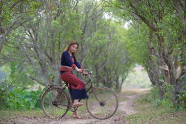 Eski bir bisikleti kabile içinde oturan genç Asyalı kadınlar pirinç elbise 