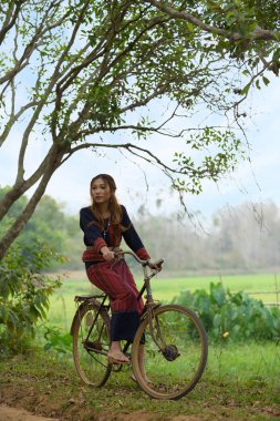 Eski bir bisikleti kabile içinde oturan genç Asyalı kadınlar pirinç elbise 