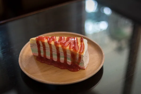 Rainbow crape cake on wooden plate. — Stock Photo, Image