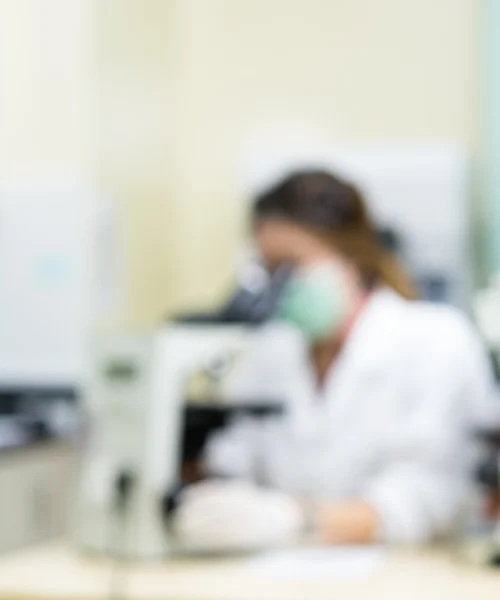 Visão lateral de uma mulher cientista desfocada usando microscópio em trabalho de parto — Fotografia de Stock