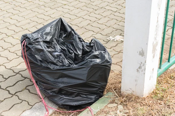 Черные мешки для мусора рядом с бетонным столбом на открытом стадионе . — стоковое фото