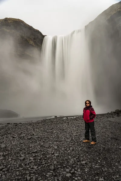 Mujer de pie frente a la cascada — Foto de Stock