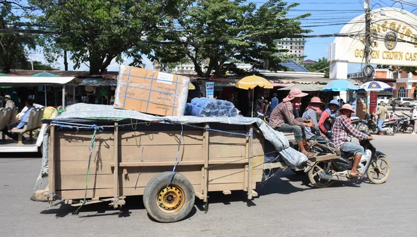 Arbejdstagere transporterer varer med motorcykel og vogn i den thailandsk-cambodjanske grænseby - Stock-foto