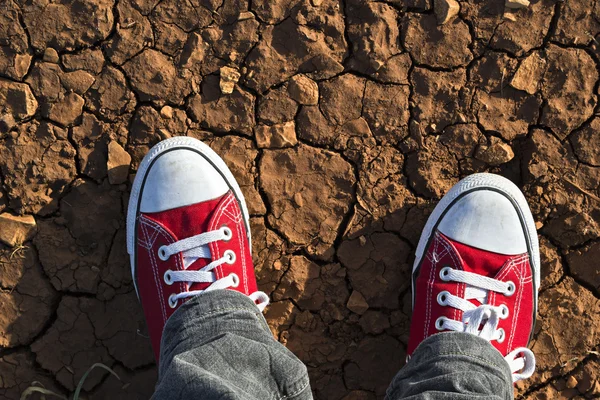 Detail of red sneakers on dry ground seen from above — Stock Photo, Image