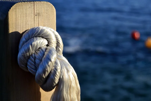 Detail of a knot with the blue sea and some buoys in the background — Stock Photo, Image