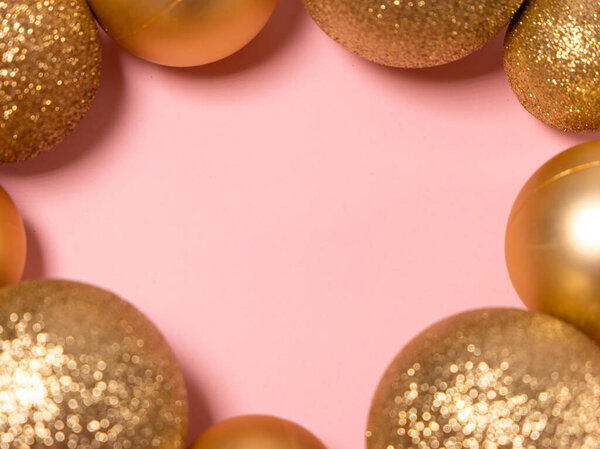 Розовый рождественский фон с золотыми шариками. Новый год и Рождество 2021 года. Место для текста.
