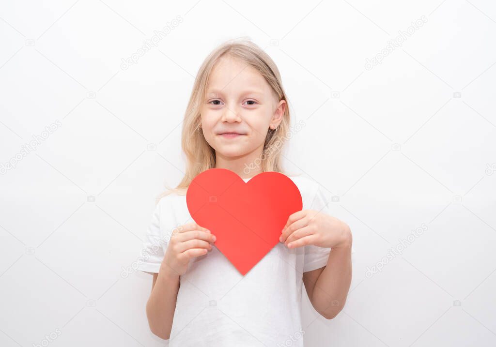 Little girl in a white T-shirt holding a red heart on a white background. Greeting card for valentine's day, mother's day, father's day.