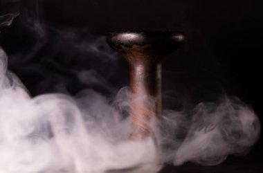 Duman arkaplanındaki toprak kaplama nargile kasesi. Nargile tütünü.