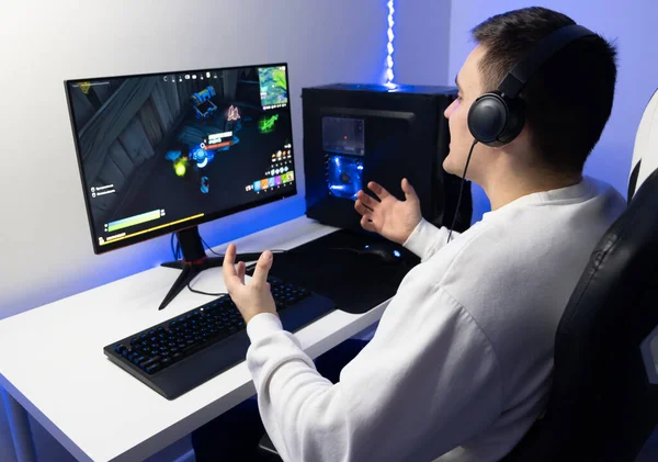 那家伙在玩网络游戏 游戏者坐在一间蓝色霓虹灯房里的电脑前 — 图库照片
