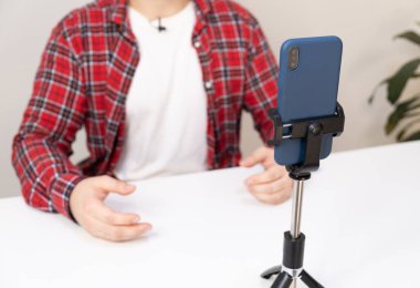 Kırmızı tişörtlü bir adam telefonla yayın yapıyor. blogcu abonelerle canlı bağlantı kuruyor.