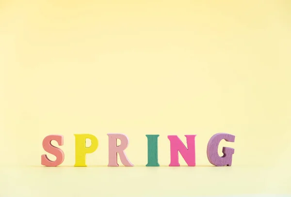 Palavra Spring Letras Cor Madeira Fundo Pastel Amarelo — Fotografia de Stock