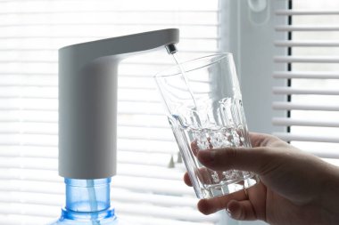 Erkek elleri şişeden bardağa otomatik pompa kullanarak temiz su döker..