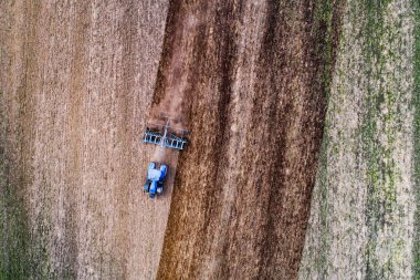 Kırsal Estonya 'da ilkbaharda ekin tarlası hazırlayan mavi bir tarım traktörü..