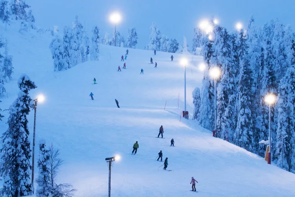 Skiers descending on a snowy hill in Ruka ski resort near Kuusamo, Northern Finland.